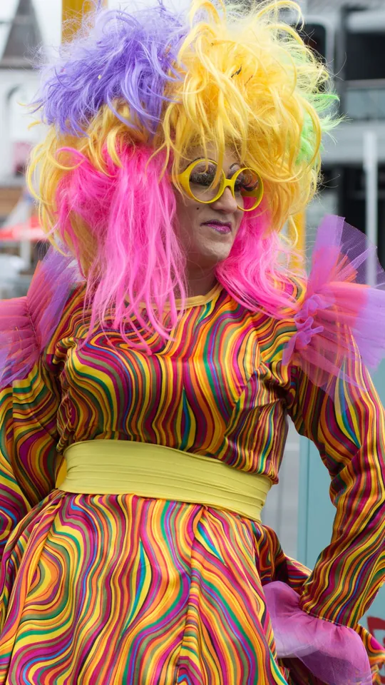 Person in a rainbow wig, sunglasses and a swirly psychedelic outfit