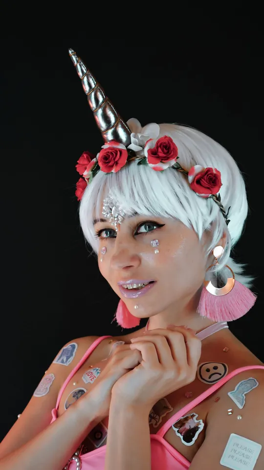 Smiling woman in a white wig with a unicorn horn and rose crown
