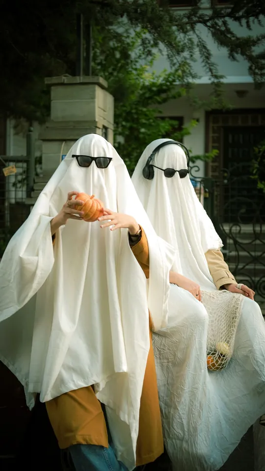 Two friends in white sheet ghost costumes and black sunglasses